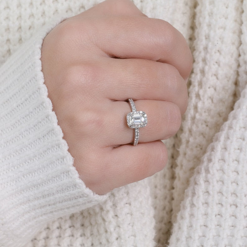 Emerald cut lab grown diamond halo engagement ring with accent stones set in a polished gold band