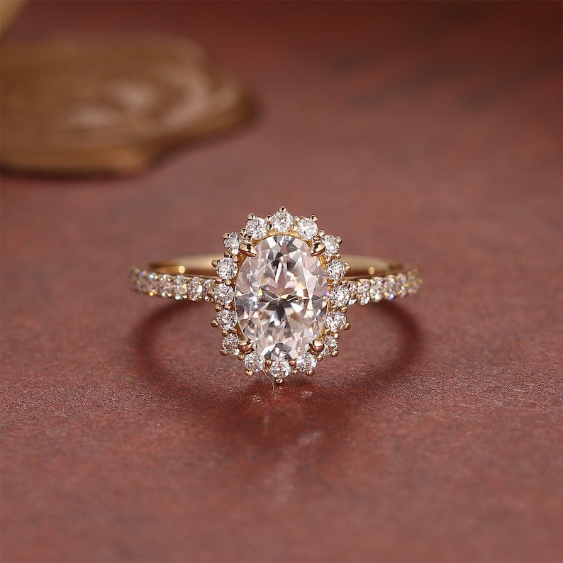 Oval cut lab grown diamond halo pavé engagement ring with side stones set in polished gold band for added brilliance