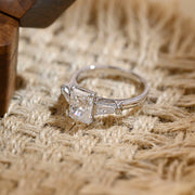 Radiant cut lab grown diamond three stone engagement ring with side stones in elegant prong setting on polished gold band