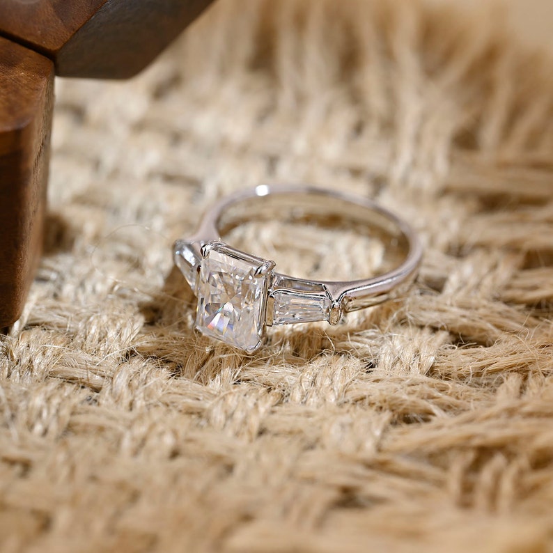 Radiant cut lab grown diamond three stone engagement ring with side stones in elegant prong setting on polished gold band