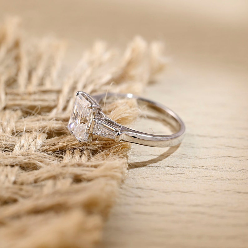 Radiant cut lab grown diamond three stone engagement ring with side stones in elegant prong setting on polished gold band