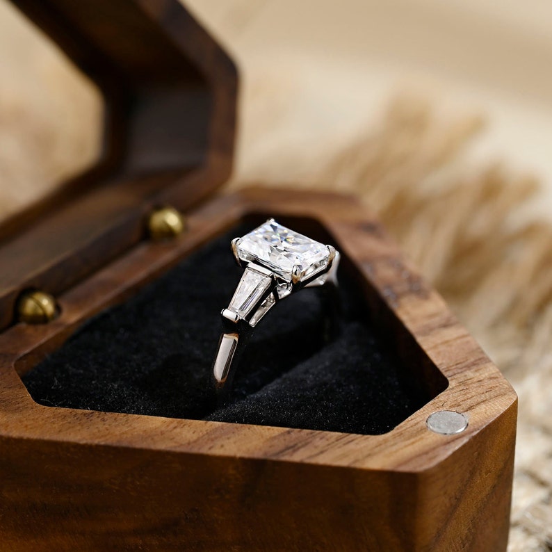 Radiant cut lab grown diamond three stone engagement ring with side stones in elegant prong setting on polished gold band