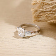 Radiant cut lab grown diamond three stone engagement ring with side stones in elegant prong setting on polished gold band