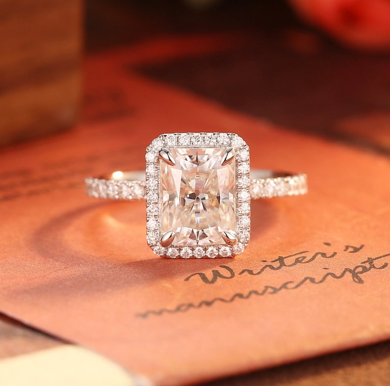 Radiant cut lab grown diamond halo pavé engagement ring with side stones, set in elegant prong design on polished gold band
