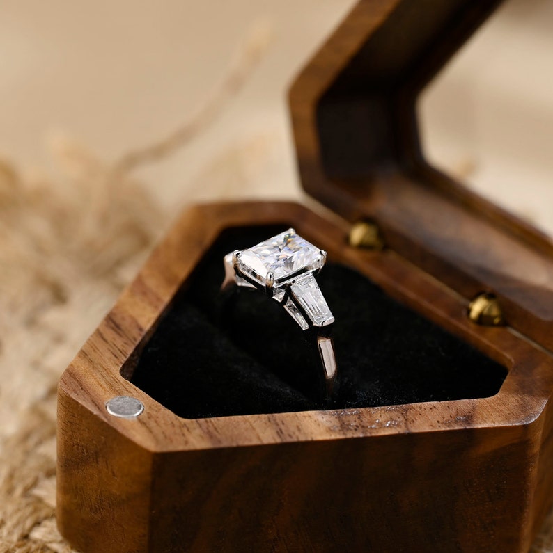 Radiant cut lab grown diamond three stone engagement ring with side stones in elegant prong setting on polished gold band