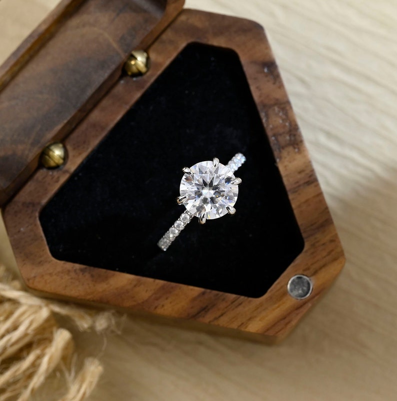 Round cut lab grown diamond hidden halo pavé engagement ring with accent stones set in a polished gold band