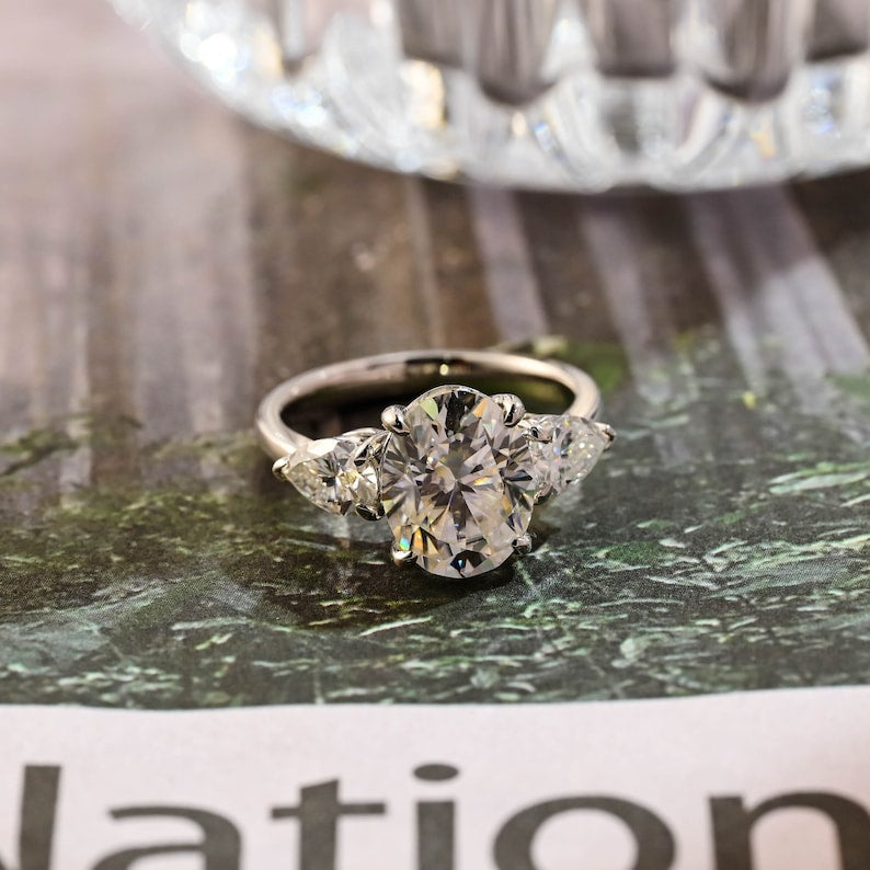 Oval cut lab grown diamond three stone engagement ring with side stones in classic prong setting on polished gold band