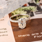 Oval cut lab grown diamond halo pavé engagement ring with side stones, set in prong design on polished gold band