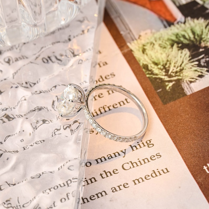 Oval cut lab grown diamond halo pavé engagement ring with side stones, set in prong design on polished gold band