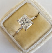 Radiant cut lab grown diamond pavé engagement ring with sparkling side stones set on polished gold band in prong setting