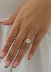 Radiant cut lab grown diamond engagement ring with hidden halo setting and prong design on polished gold band
