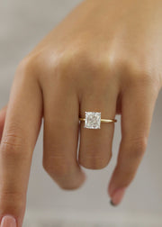 Radiant cut lab grown diamond engagement ring with hidden halo setting and prong design on polished gold band