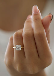 Radiant cut lab grown diamond engagement ring with hidden halo setting and prong design on polished gold band