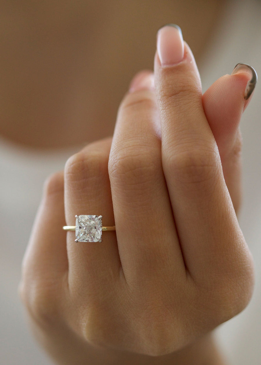 Radiant cut lab grown diamond engagement ring with hidden halo setting and prong design on polished gold band