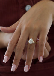 Pear cut lab grown diamond engagement ring with halo setting, featuring accent stones on a polished gold band