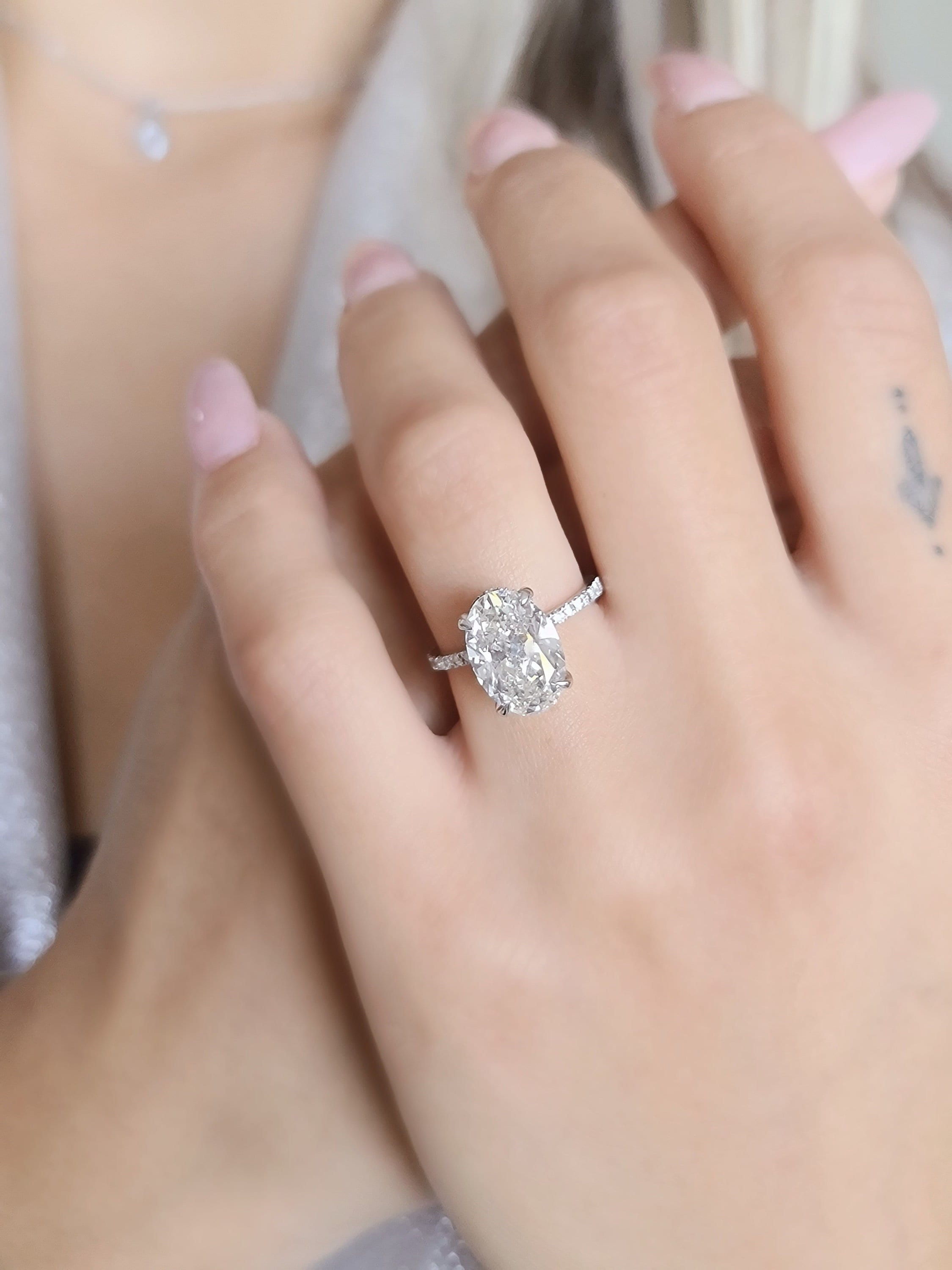 Oval cut lab grown diamond hidden halo engagement ring with prong setting and delicate band in polished gold