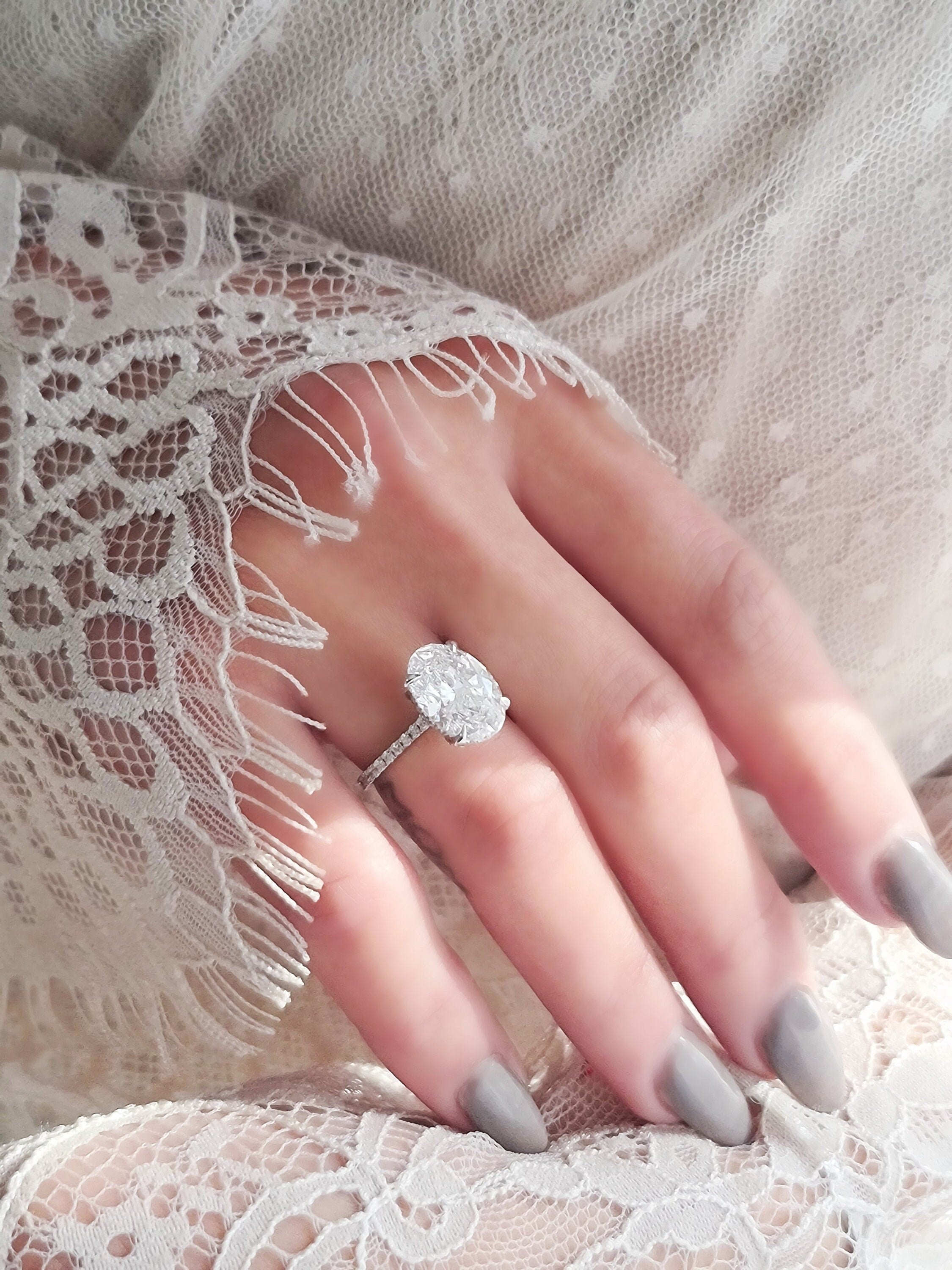 Oval cut lab grown diamond hidden halo engagement ring with delicate pavé accents set in polished gold band