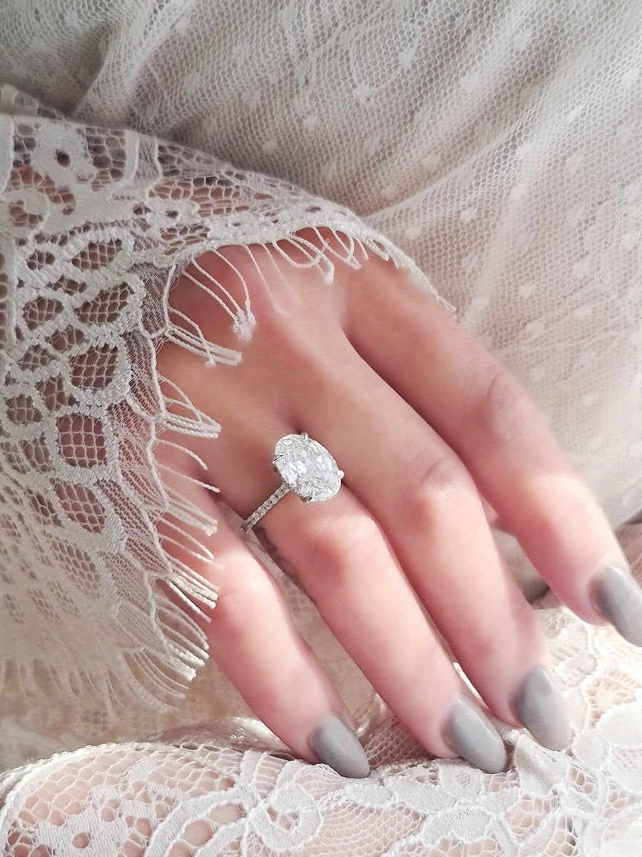 Oval cut lab grown diamond hidden halo engagement ring with delicate pavé accents set in polished gold band